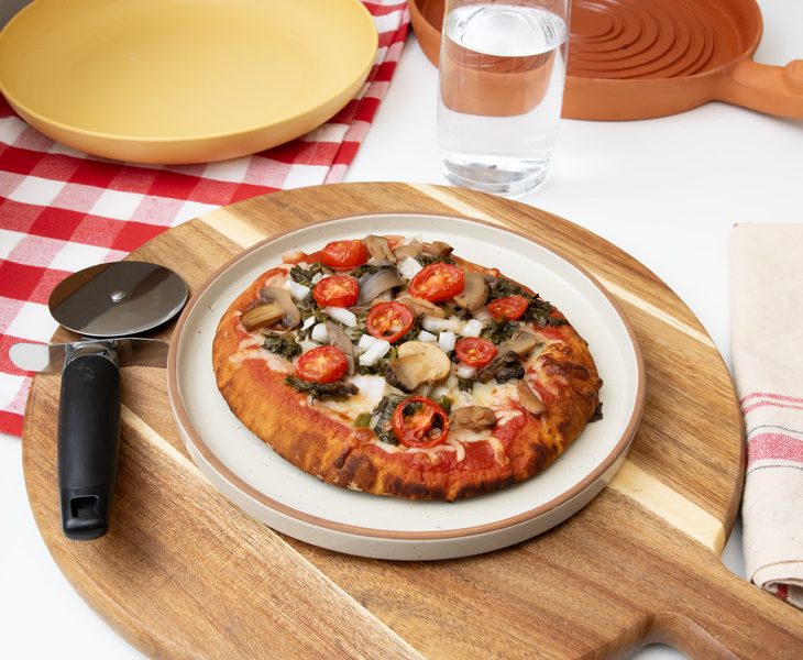 small pizza on a plate next to a pizza cutter