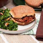 sloppy joe sandwich next to dark green coleslaw on a plate