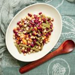 beans in a bowl next to a spoon on table